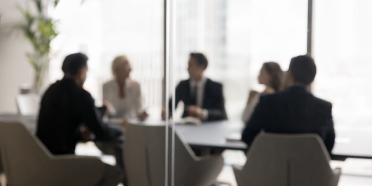 Group of businesspeople blurry behind glass doors of conference room